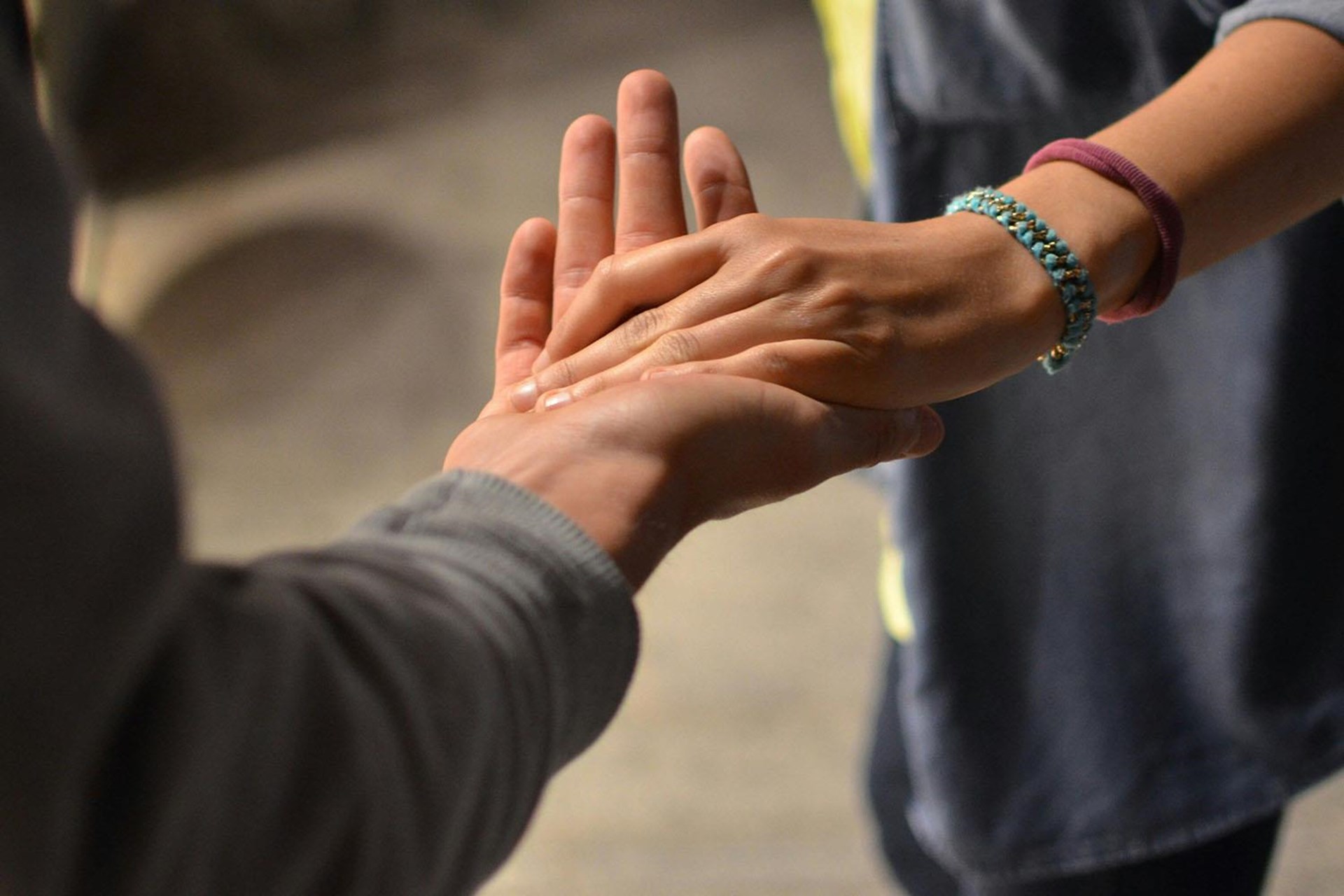 Das Bild zeigt eine ältere Hand, in die sich eine jüngere Hand mit zwei Armbändern legt.