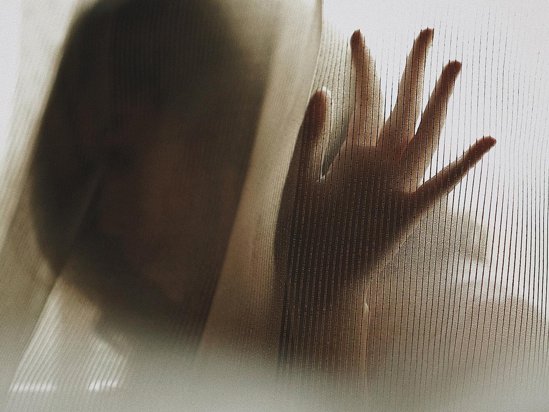 Schwarz-weiß Bilder einer Frau hinter einem halbtransparenten Vorhang.
