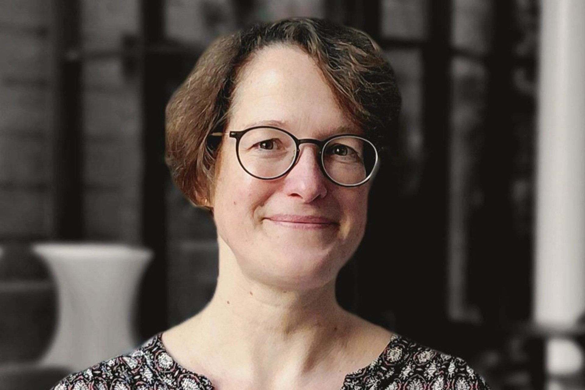 Das Bild zeigt eine hübsche Frau mit Brille, die in die Kamera lächelt.