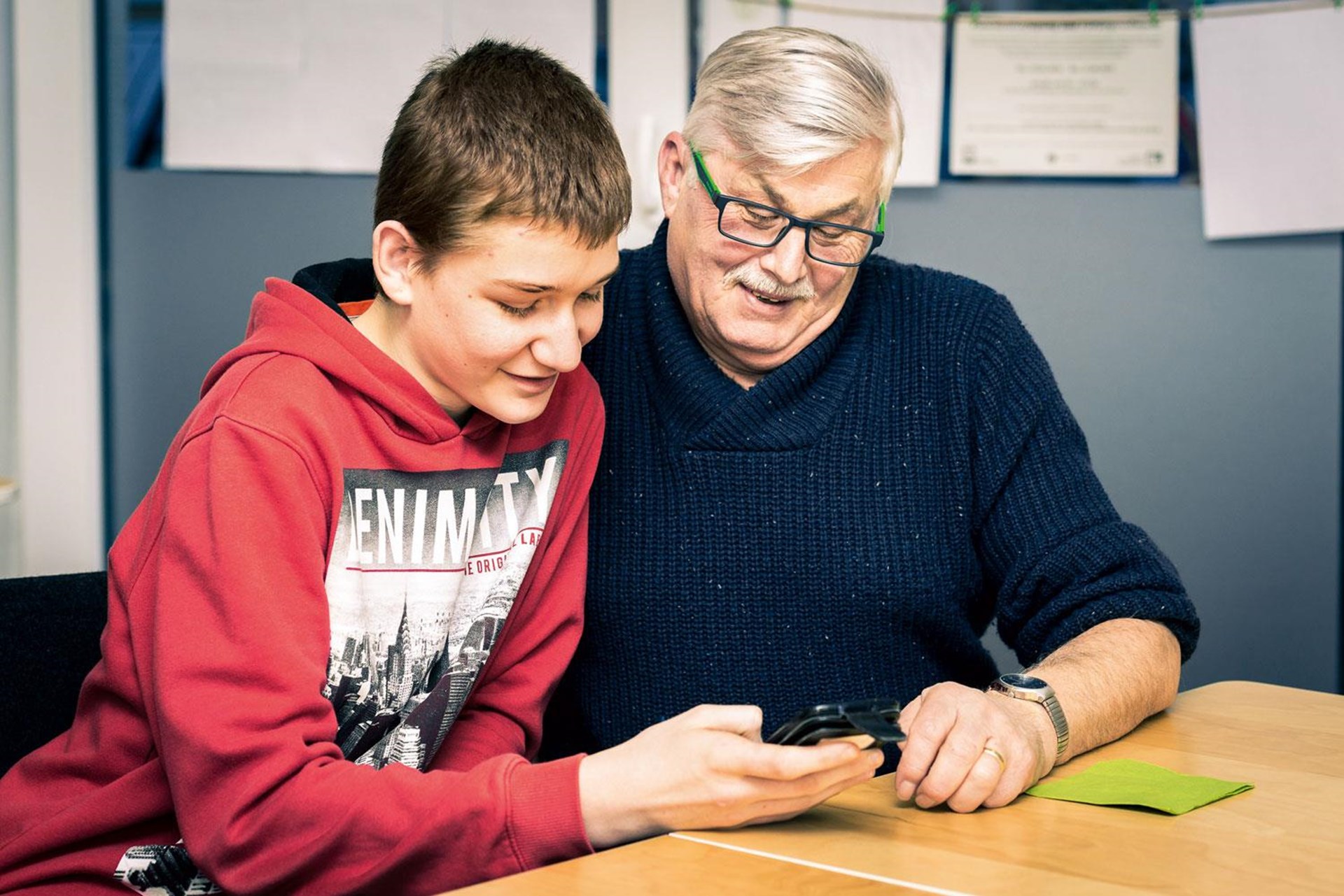 Ein Junge erklärt einem Mann die Funtionen eines Smartphones