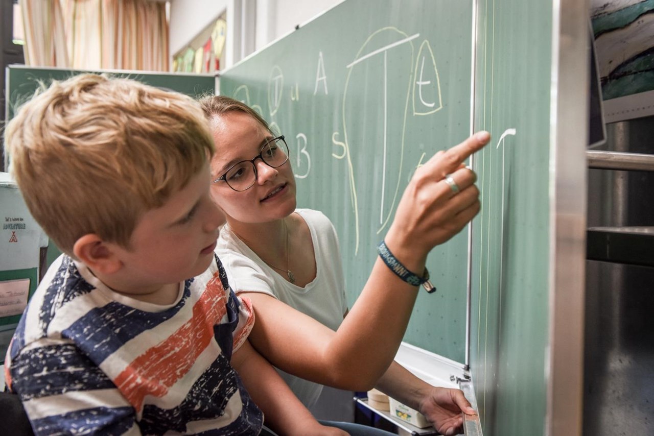 Junge Frau mit einem Jungen an Schultafel