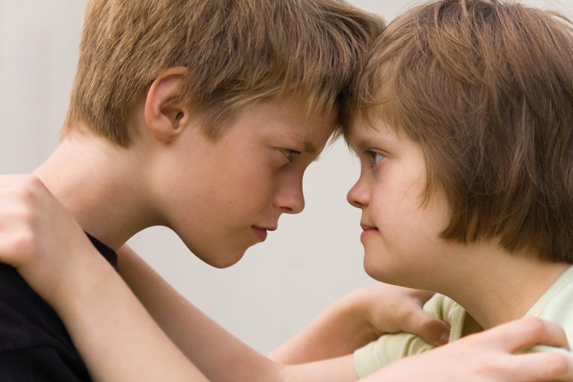 Ein Schüler umarmt eine Schülerin mit DOWN-Syndrom (Nahaufnahme der Gesichter)