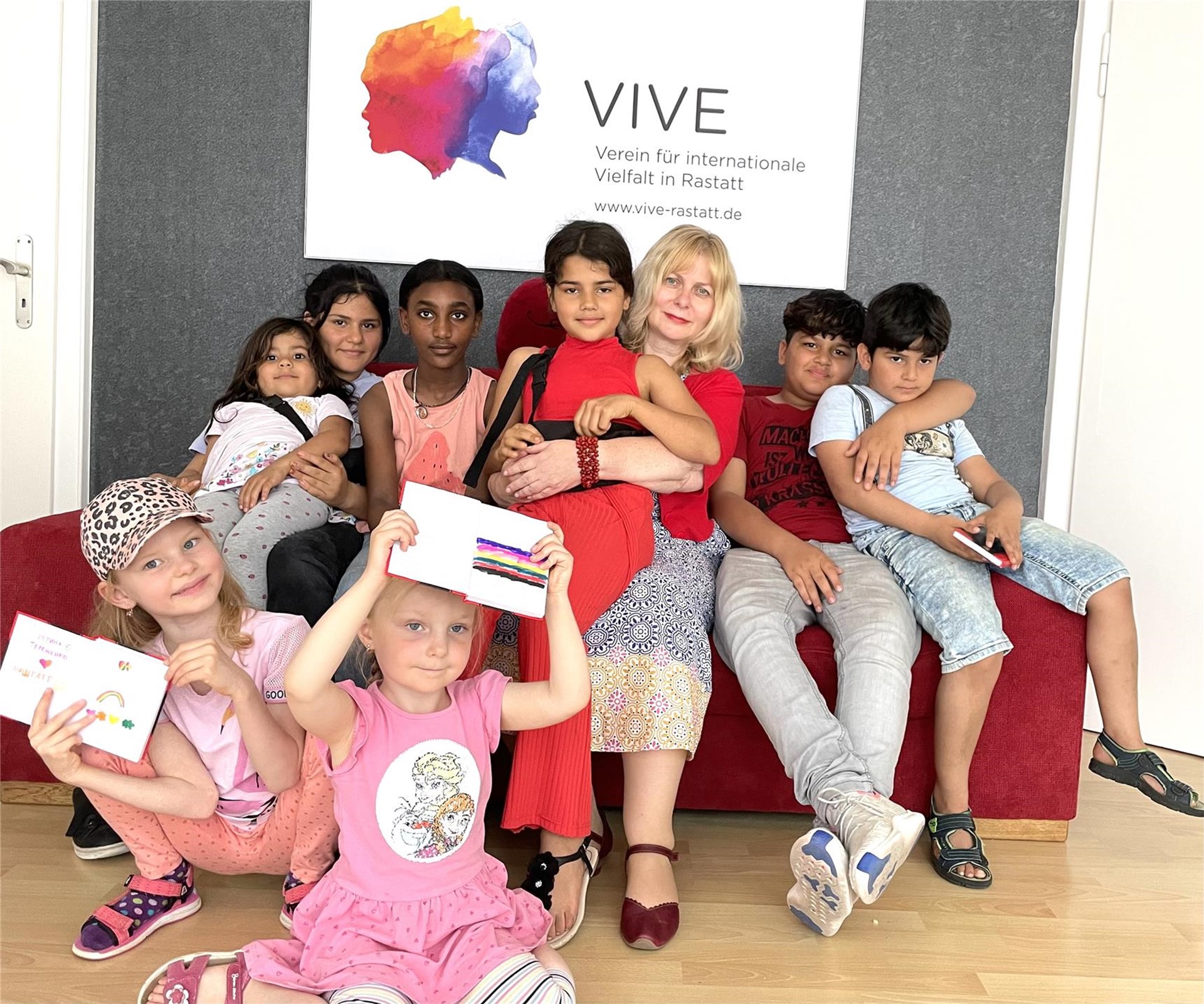 Eine Gruppe von Kindern und Erwachsenen sitzt auf einer Couch und hält Karten hoch.