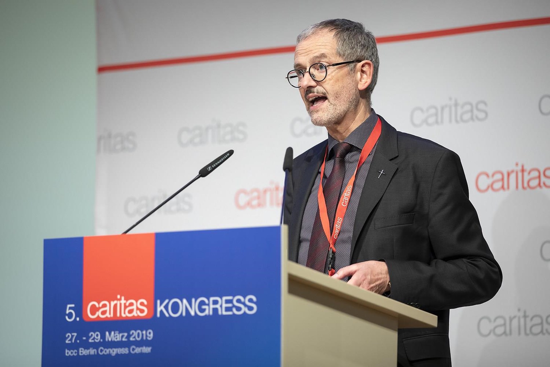 Mann spricht am Rednerpult auf dem 5. Caritas Kongress in Berlin, trägt eine Krawatte und ein Namensschild.