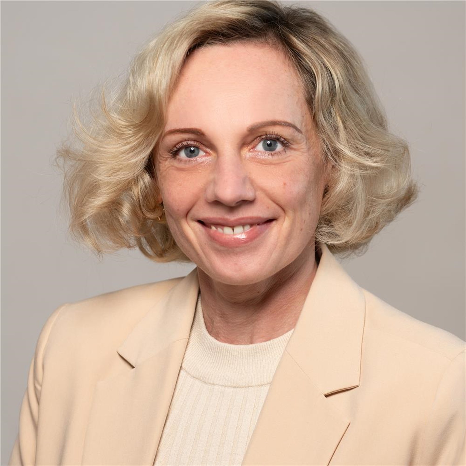 Portrait einer lächelnden Frau vor grauem Hintergrund