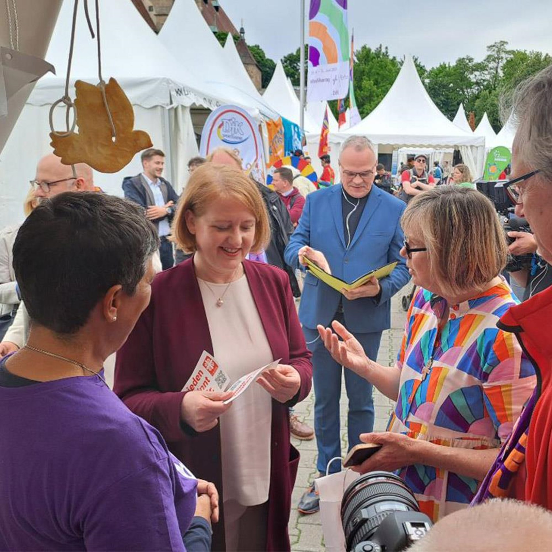 Das Bild zeigt die Caritas-Präsidentin Eva Maria Welskop-Deffaa und Vorständin Dr. Susanne Pauser im Gespräch mit Lisa Paus am Stand der Caritas beim Katholikentag 2024.