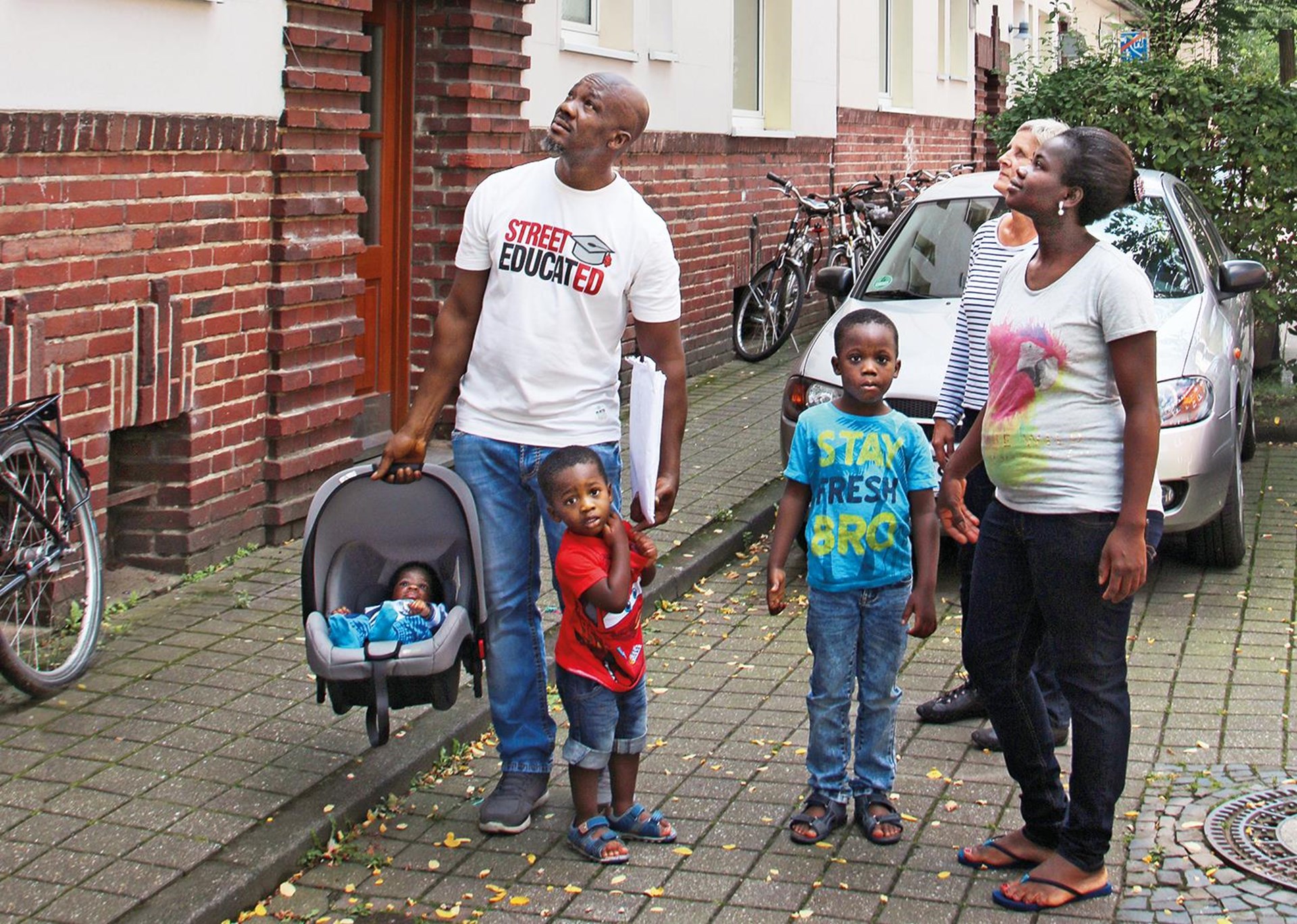 Familie mit Kleinkindern blickt auf Haus.