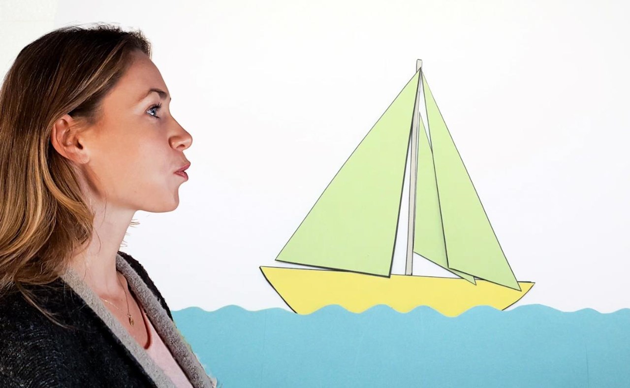  Eine Frau betrachtet ein Segelboot, das an einer Wand hängt.