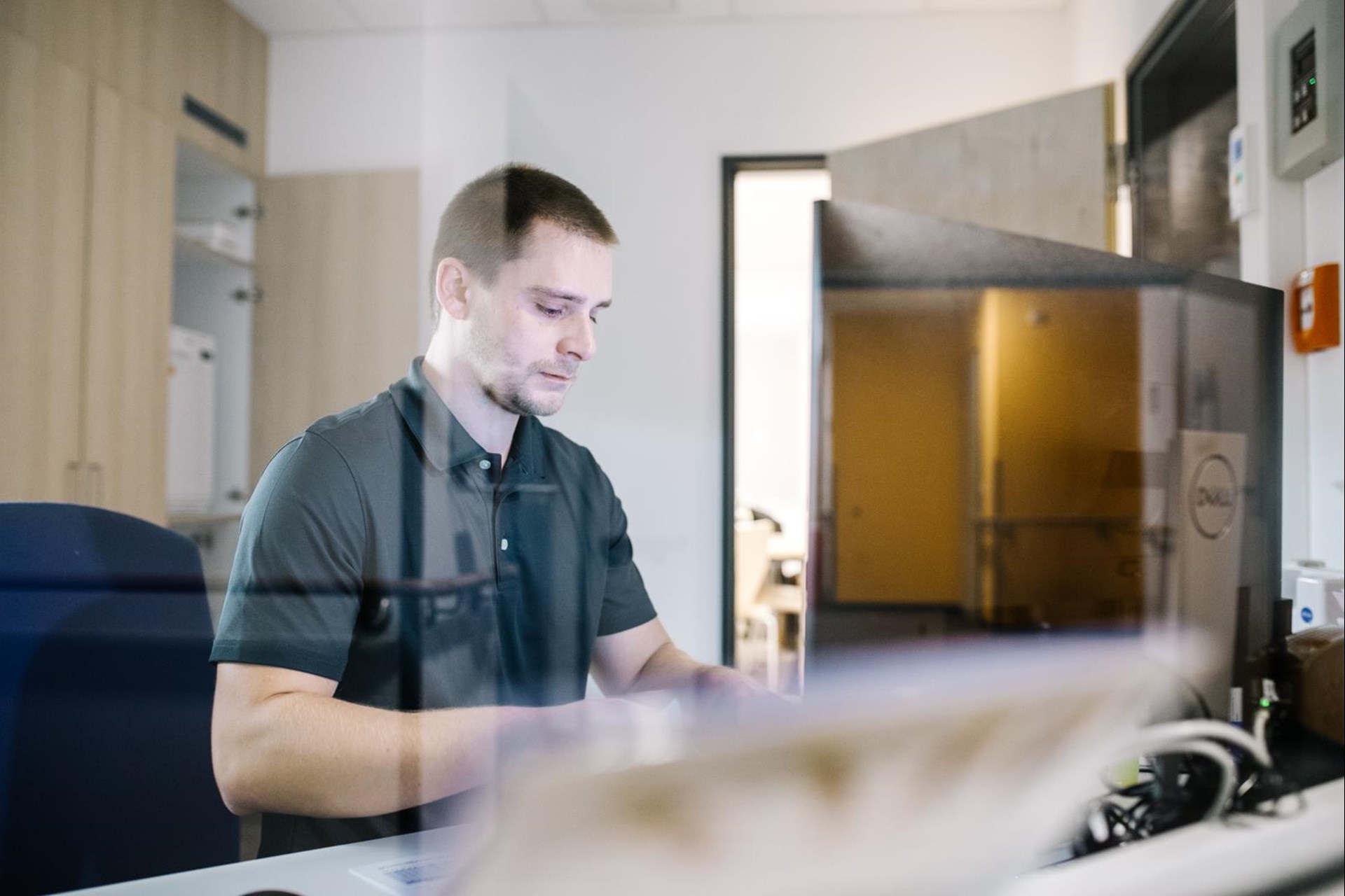 Mann hinter Glasscheibe vor Computer