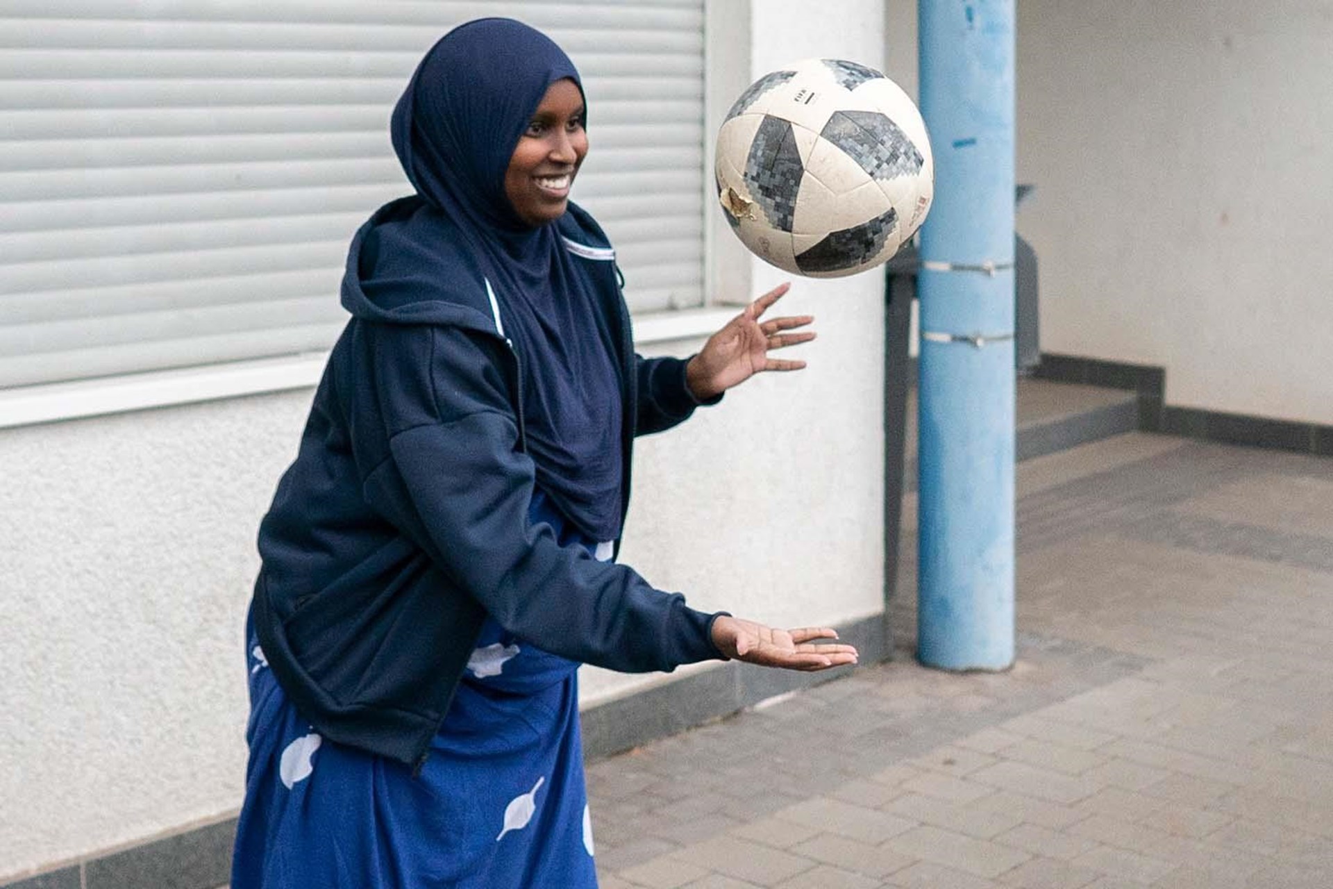 Eine Frau mit dem Kopftuch spielt Fußball.