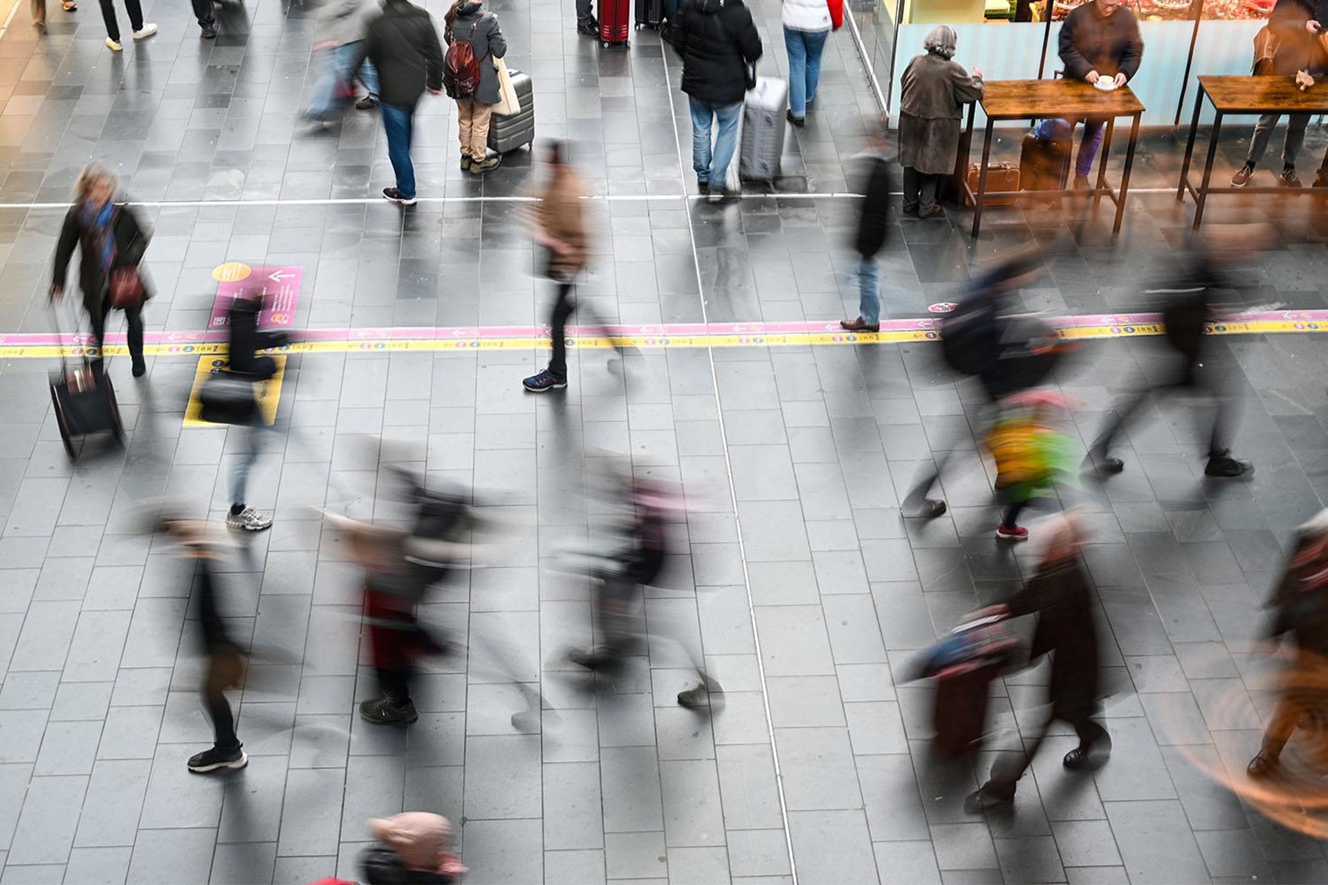 Verschwommen aufgenommene Menschen bewegen sich durch einen Bahnhof