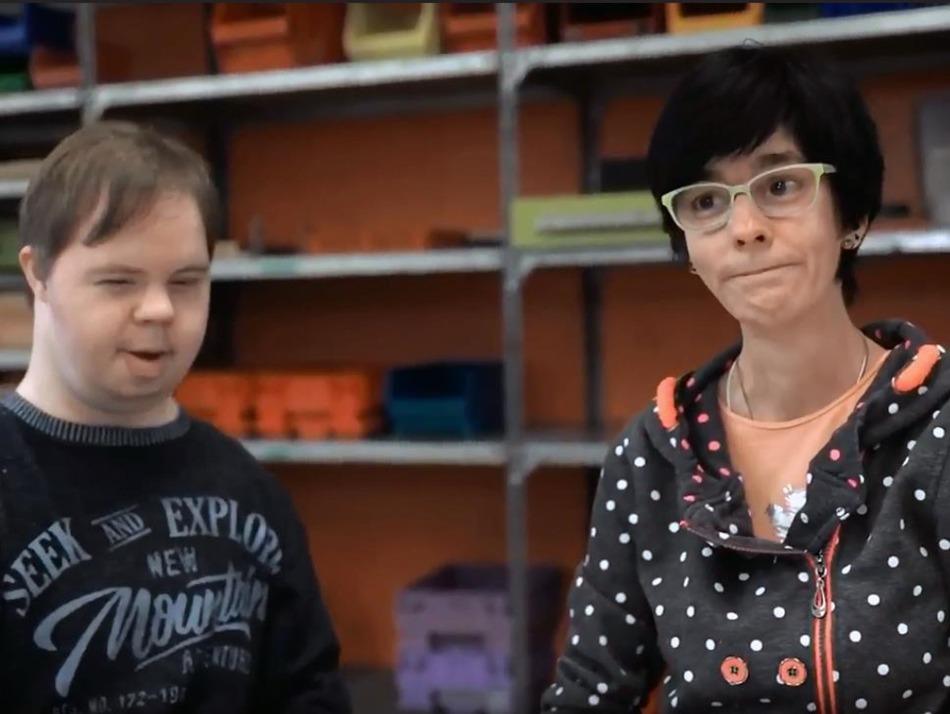 Eine Frau und ein Mann stehen vor Regalen in einem Geschäft, umgeben von verschiedenen Produkten.