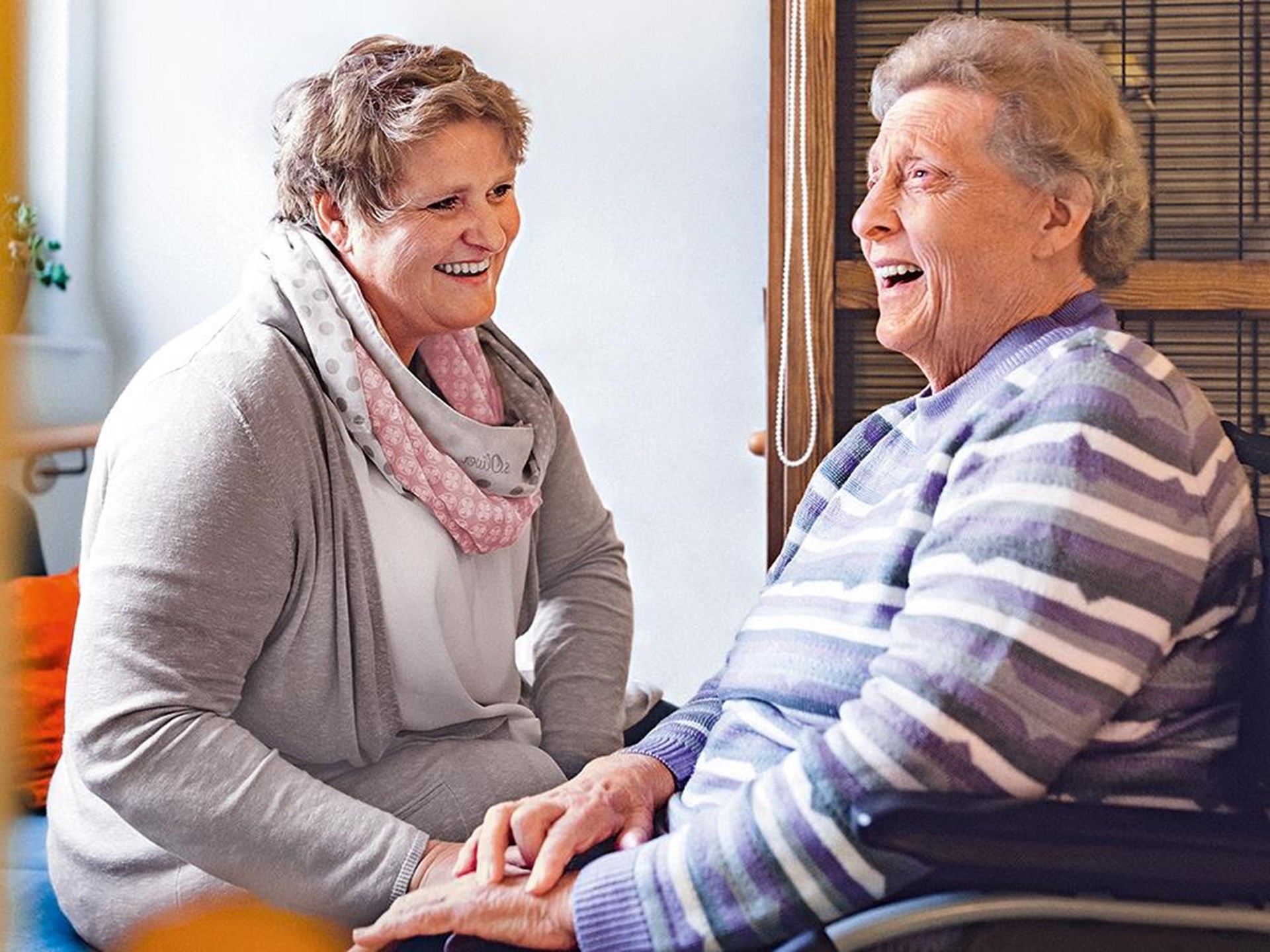 Zwei lachende Frauen sitzen zusammen