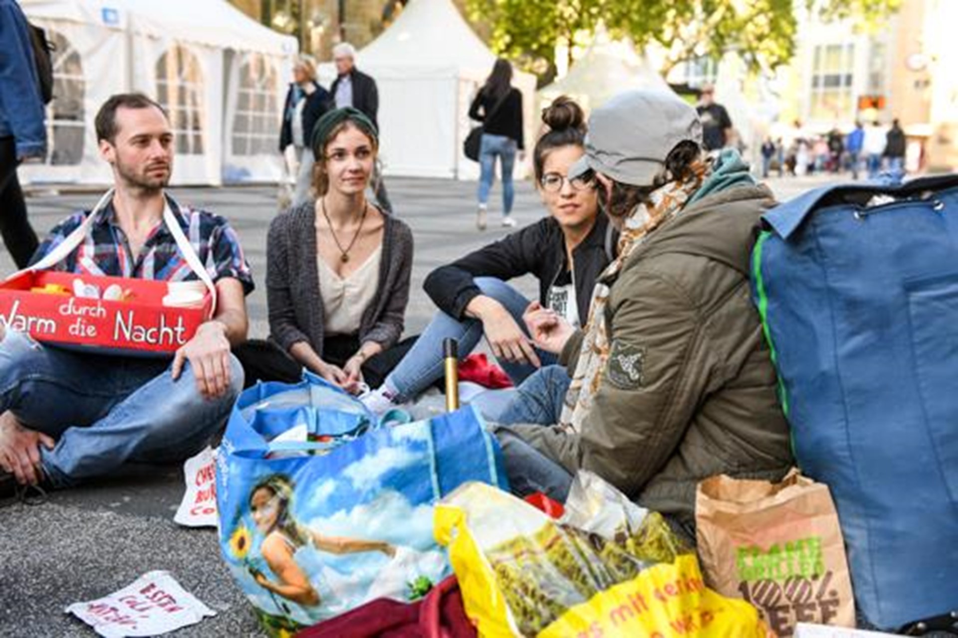 junge Menschen mit Gespräch mit einem Obdachlosen mit Plastiktüten