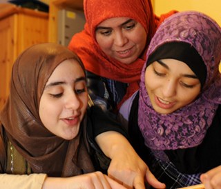 Frauen mit Migrationshintergrund schauen gemeinsam ein Buch an.