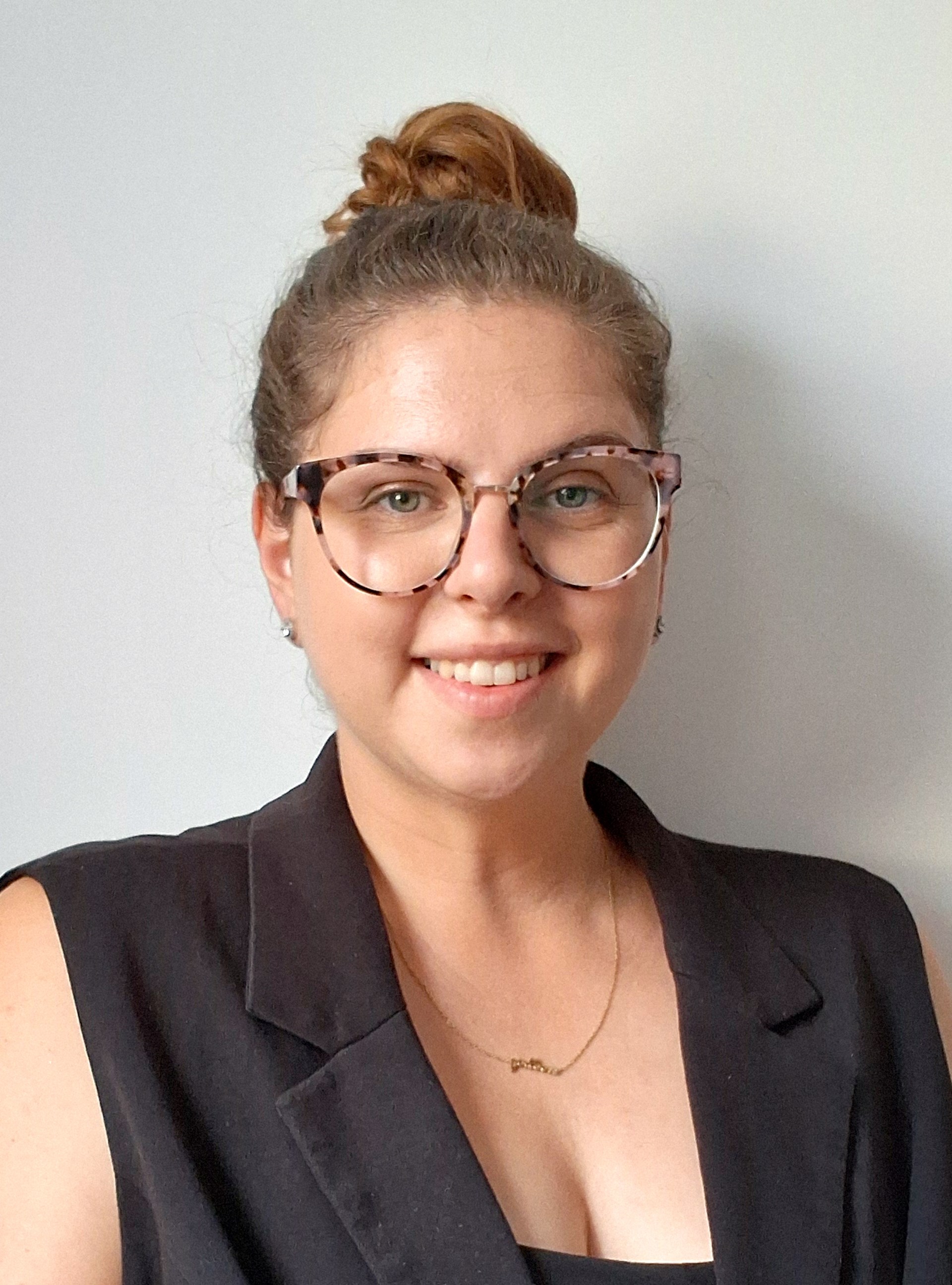 Porträtfoto einer jungen Frau mit hochgesteckten Haaren und Brille