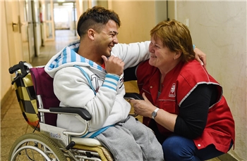 Flüchtling im Rollstuhl mit Caritasmitarbeiterin