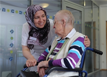 alte Frau im Rollstuhl mit einer Pflegerin