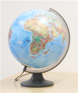 Ein Globus mit Stromkabel, der auf einem hellen Holztisch steht