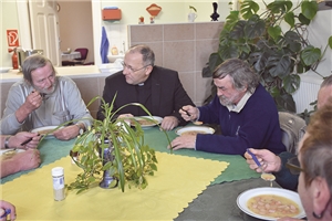 Bischof und Obdachlose essen gemeinsam