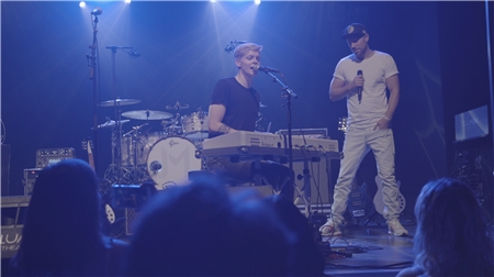 Junger Mann am Schlagzeug und ein Mann neben ihm am Mikrofon.