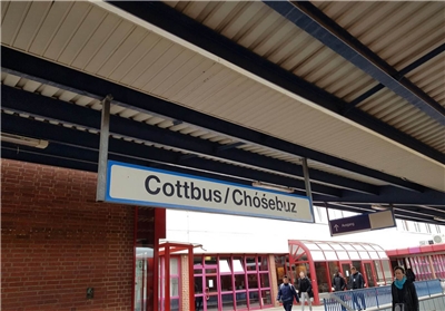 Ein Ortsschild an Gleis 1 des Cottbusser Hauptbahnhofs zeigt den Namen der Stadt auf Deutsch und auf Sorbisch.