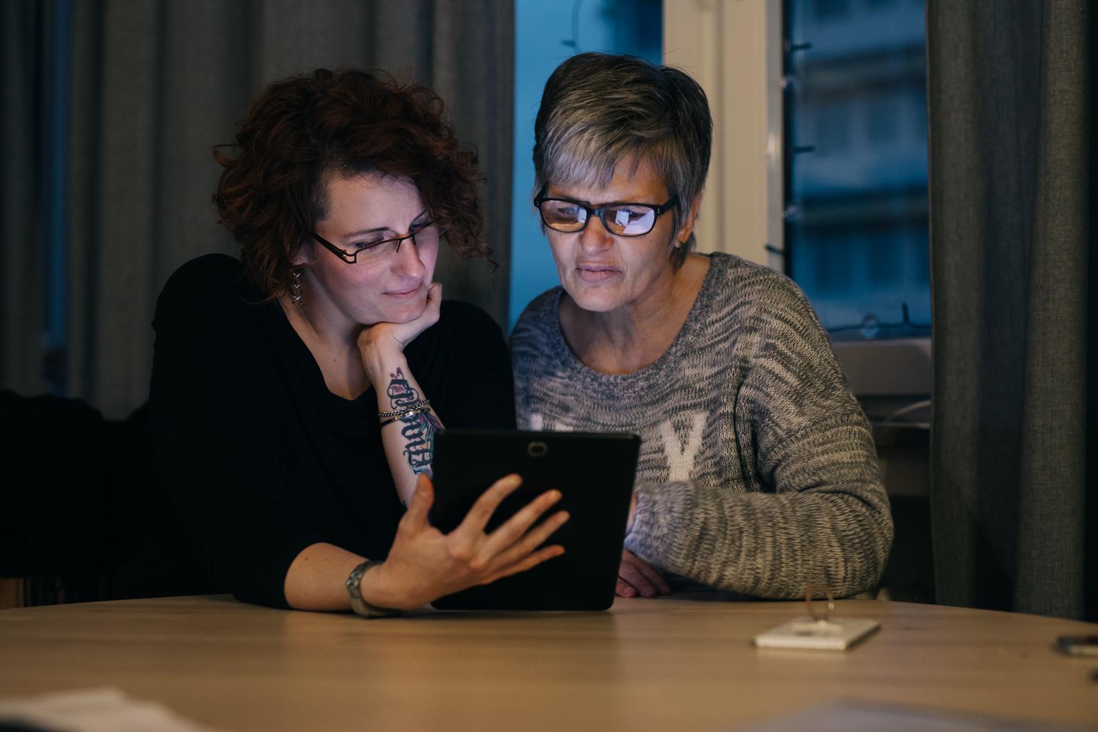Zwei Frauen mit Brillen blicken in ein Computertablet