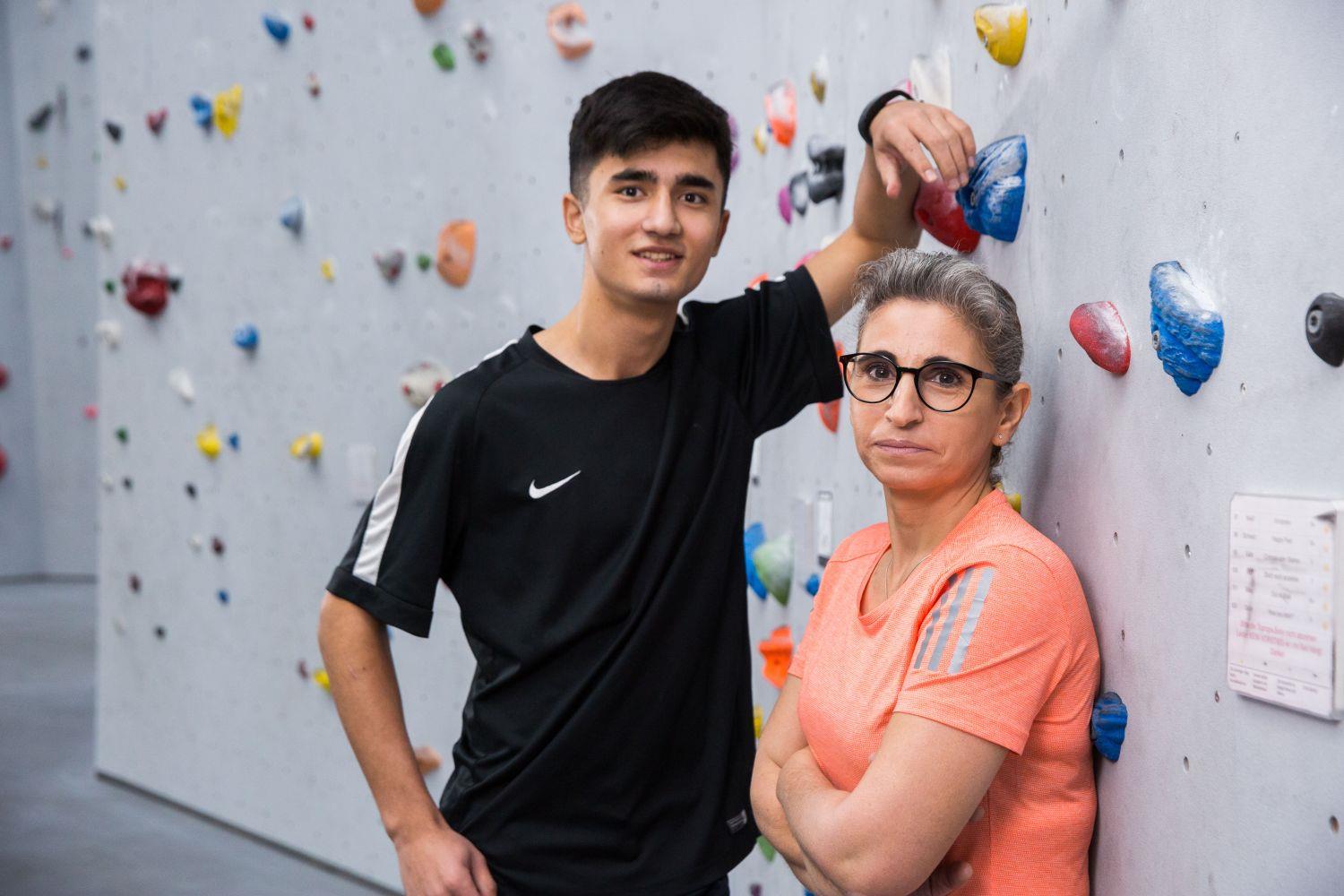 Junger Mann und Frau stehen vor einer Kletterwand