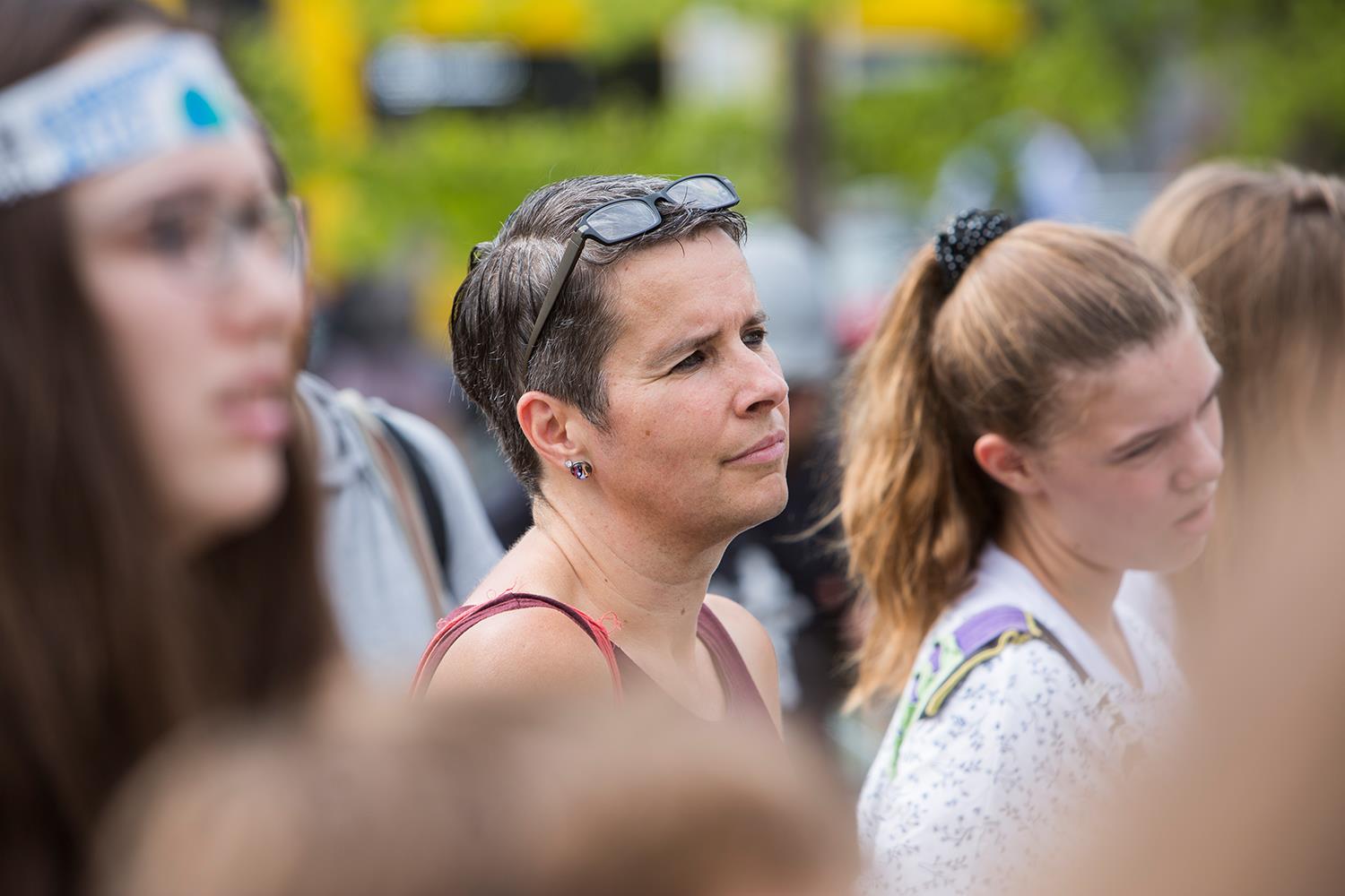Eine Frau, die ihre Brille auf die Stirn hochgezogen hat, steht in einer Menschenmenge