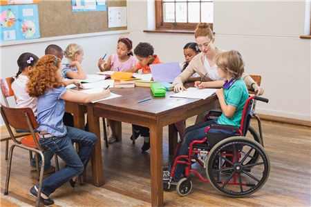 Kind im Rollstuhl in einer Arbeitsgruppe Gleichaltriger.