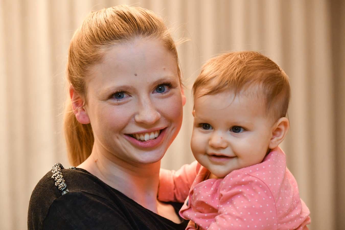 Blonde junge Frau mit Baby im Arm