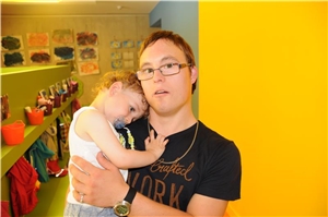 Mann mit Downsyndrom hat Kleinkind im Arm