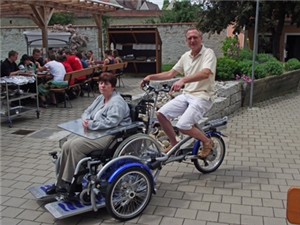 Mann fährt alte Frau in elektrisch unterstütztem Rollstuhltransporter