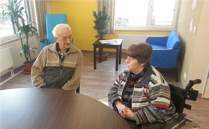 älterer Mann und ältere Frau sitzen um Tisch herum