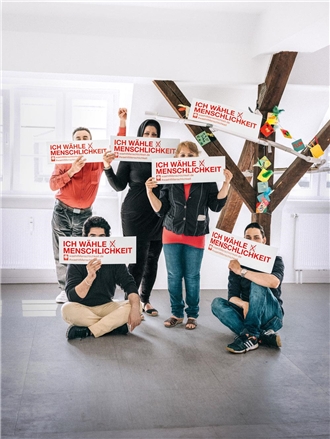 Gruppenbild von fünf Menschen, die Schilder hochhalten