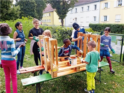 Eine Gruppe von Kindern werkelt an einer Art Tisch aus Holzpaletten.