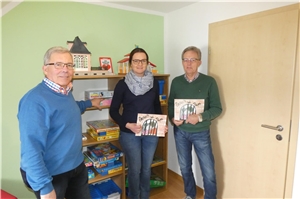 Hans-Peter Pesch (links), Melanie Begon und Josef Heinz zeigen die Kinderbücher und Spiele, die sie während der Betreuung der Kinder einsetzen