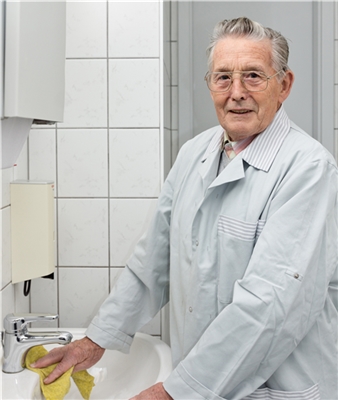 Alter Mann putzt Waschbecken