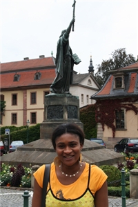 Nwokey befindet sich in Fulda an der Statur von Bonifatius. Sie lächelt glücklich.