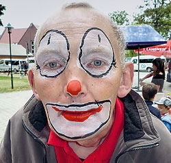 Ein Mann mittleren Alters schaut als Clown geschminkt in die Kamera