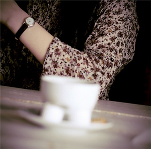 Kaffeetasse mit Arm im Hintergrund