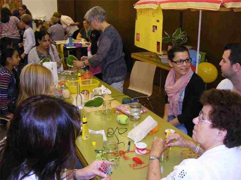 BesucherInnen des Mehrgenerationenhauses basteln an einem langen Tisch. (Caritasverband Rhein-Hunsrück-Nahe)